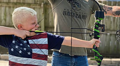 Young boy aiming a compound bow